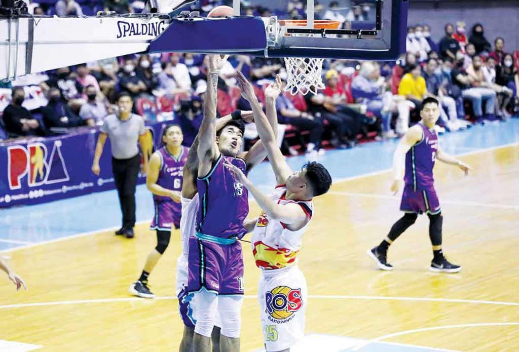 Converge FiberXers’ Justin Arana still managed to put up a shot despite being clobbered by the defense of Rain or Shine Elasto Painters. (PBA Media Bureau photo)