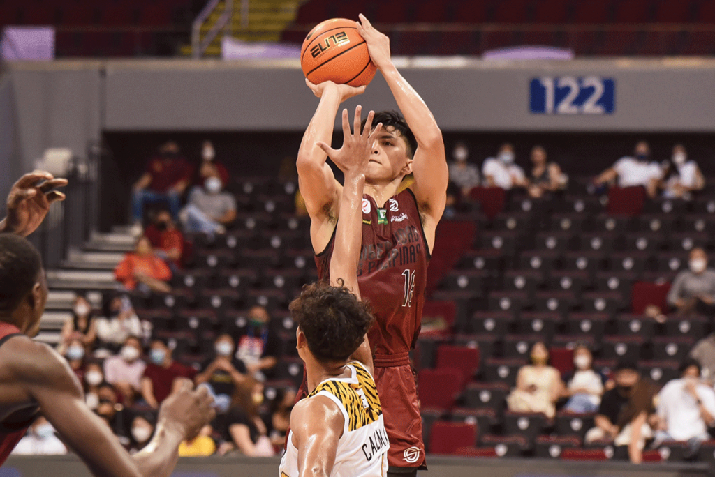 Negrense Harold Alarcon of the University of the Philippines Fighting Maroons shoots over the defense of University of Santo Tomas Growling Tigers' Nicael Cabañero. (UAAP photo)