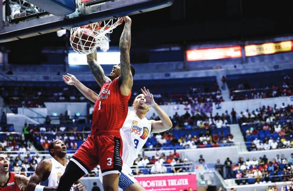 Barangay Ginebra San Miguel Kings’ Jamie Malonzo scores on a two-handed dunk after evading the defense of Negrense Paul Varilla of TNT Tropang Giga. (PBA photo)