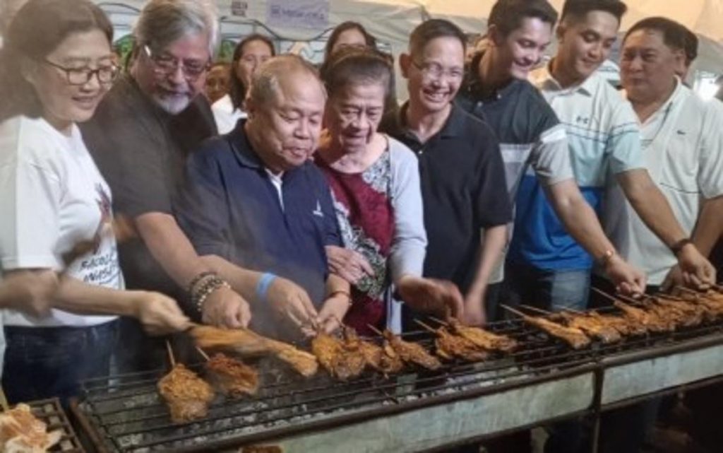 Officials of Bacolod City and guests check out chicken inasal cooked on a portion of the 320-meter-long grilling station set up along the main road to culminate the three-day Chicken Inasal Festival on Sunday night, May 28, 2023. At least 3,000 sticks of various chicken parts were grilled during the event. (Nanette L. Guadalquiver / PNA photo)