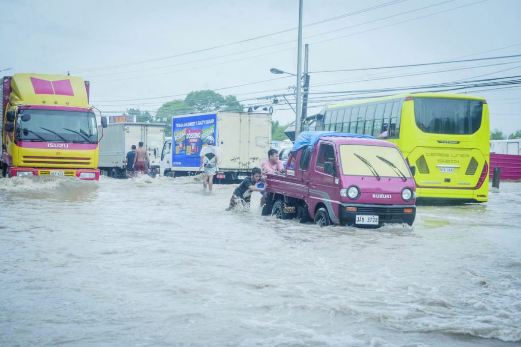 Vehicles wade through knee-deep floods due to the heavy rainfall brought by the southwest monsoon and enhanced by Super Typhoon "Egay” in Bacolod City’s Barangay Pahanocoy yesterday, July 25, 2023. (Mymy Alagaban photo) 