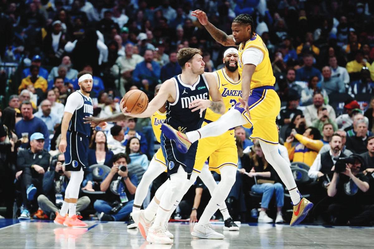 Luka Doncic of the Dallas Mavericks looks for a pass beyond Cam Reddish of the Los Angeles Lakers at American Airlines Center in Dallas, Texas. (Tim Heitman / Getty Images via AFP)