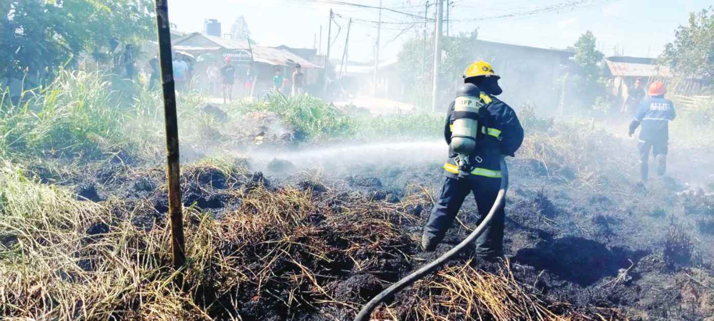 Firefighters extinguish a grass fire at Purok Lote in Bacolod City’s Barangay Alijis on Saturday morning, February 3, 2024. Long periods of hot and dry weather as well as improperly discarded lighted cigarettes are some of the causes of grass fires, the Bureau of Fire Protection says. (BFP Bacolod photo)