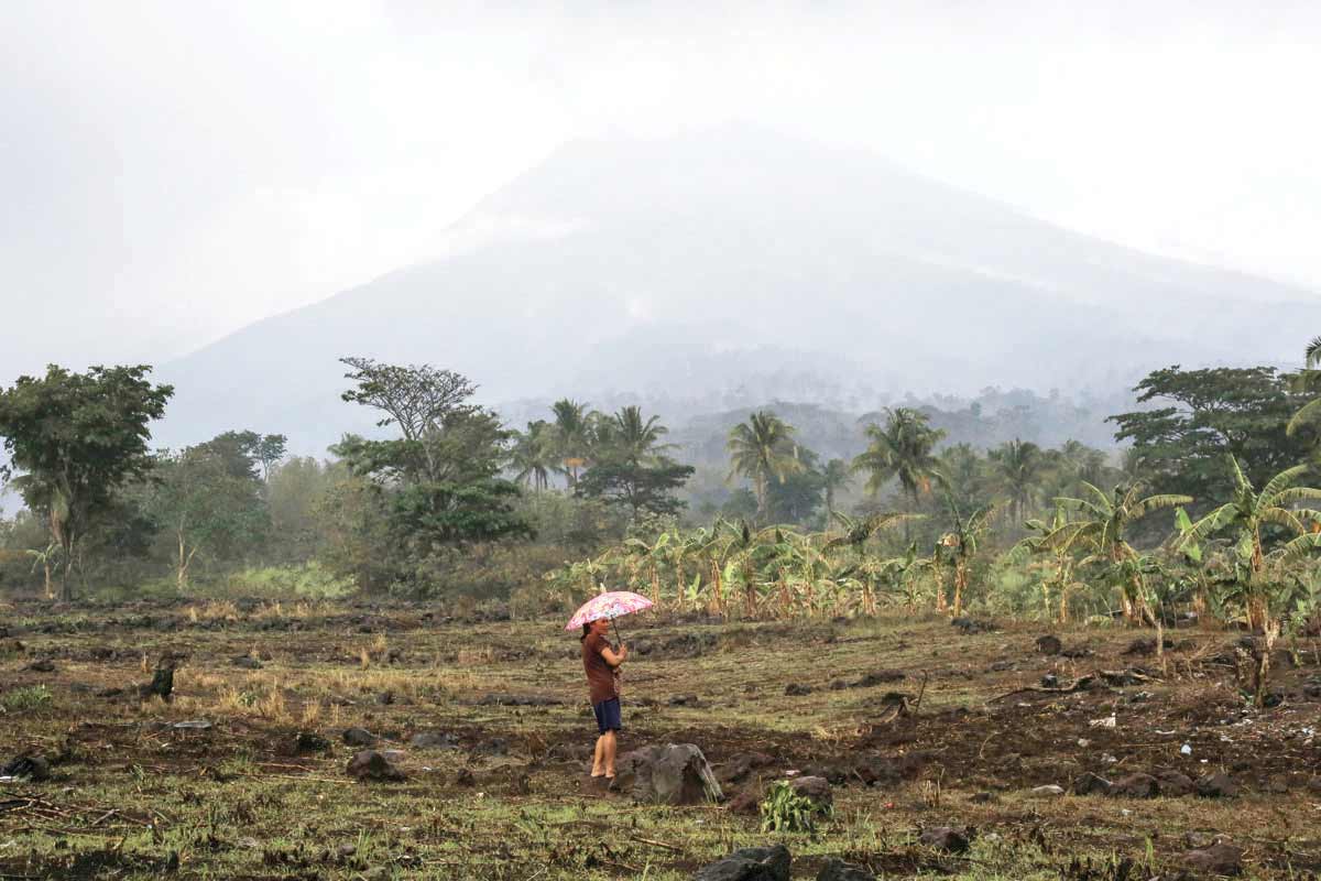 A resident holding an umbrella stands at the foot of Kanlaon Volcano in Negros Occidental’s La Castellana town on June 4, 2024. The town was placed under a state of calamity due to the eruption of Kanlaon earlier this week. (Ferdinand Edralin / AFP photo)