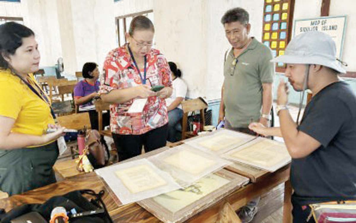 Richard Baula (right), a conservator of the National Historical Commission of the Philippines (NHCP), shows workshop participants how to preserve Spanish-era documents, at the Lazi Convent in Siquijor province on Friday, August 9, 2024. The NHCP conducted its 15th Conservation Goes to the Province seminar workshop in Lazi from August 5 to 9, 2024 to help those managing a convent museum in the municipality. (PNA photo)