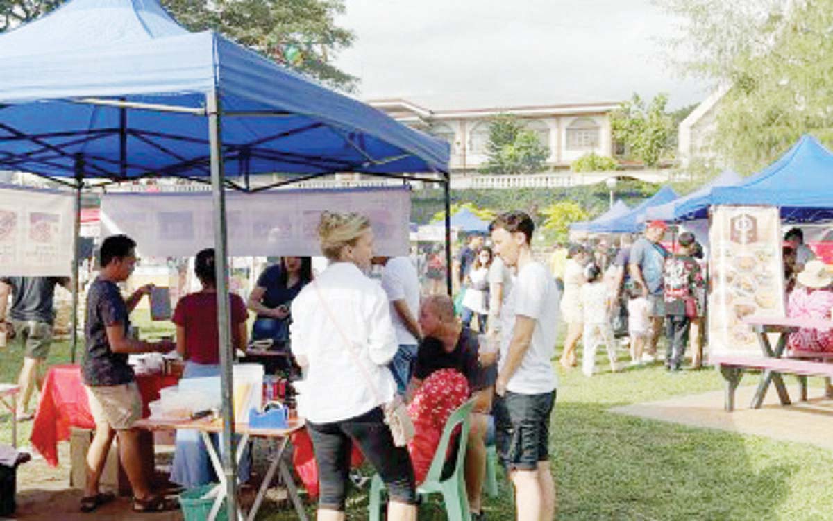 Foreigners huddle around a food stall at the regular Sunday market in Valencia, Negros Oriental. Tourist arrivals in the province rose to over 350,000 for the first half of the year, the Provincial Tourism Office says. (PNA photo)