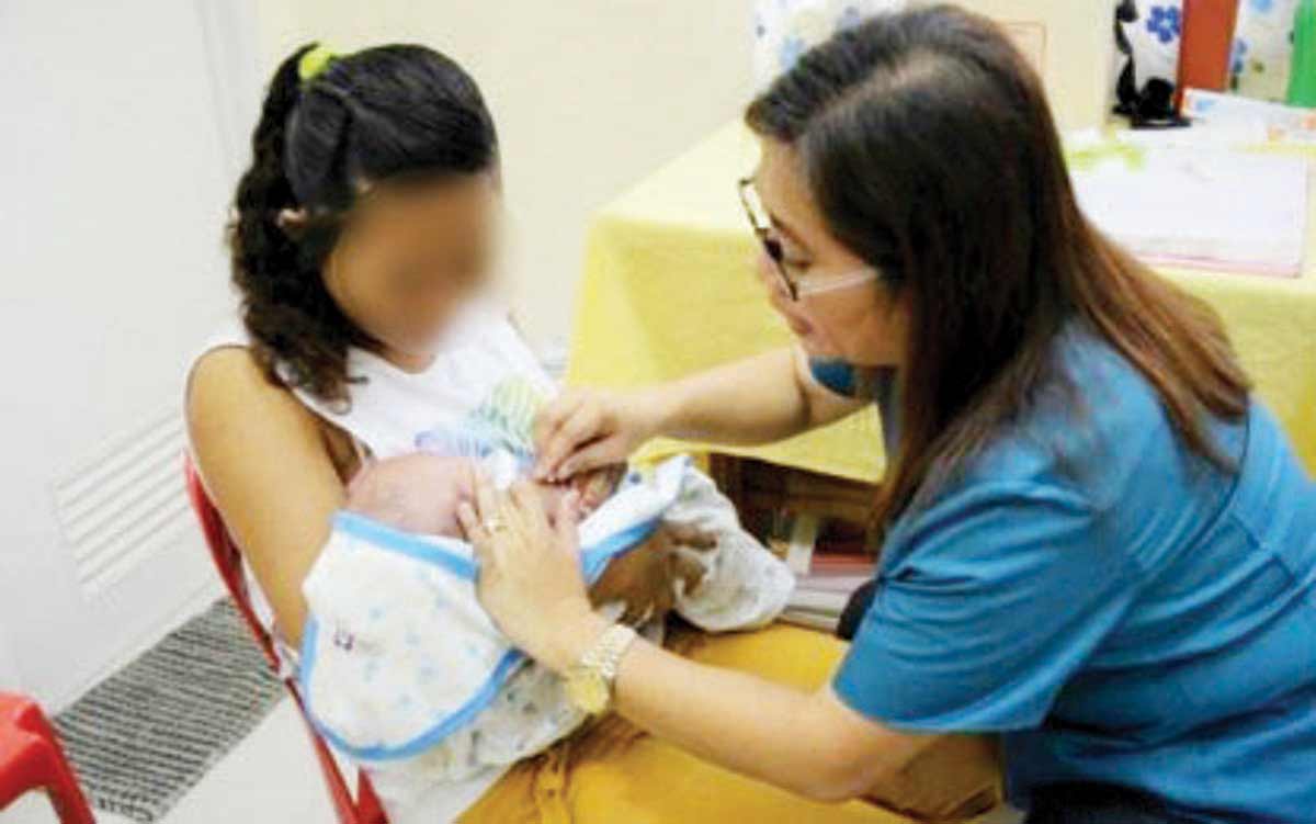 A health worker attends to a young mother and her baby in this undated photo. Teenage pregnancies in Negros Oriental in the 10-14 age bracket have remained high over the past three years, health authorities say. (Commission on Population and Development / Facebook photo)