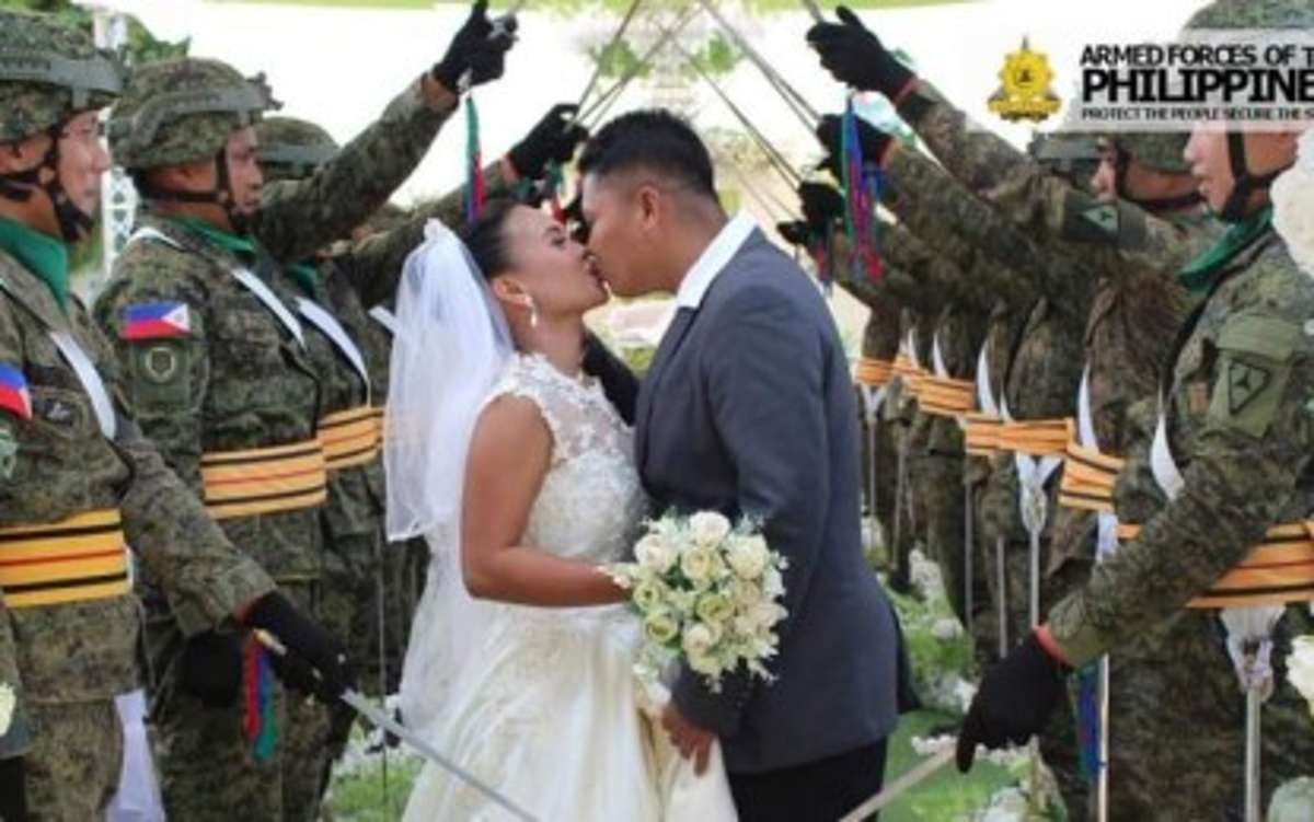 A former New People’s Army couple seals their marriage with a kiss under the arch of swords during a ceremony held at the headquarters of the Philippine Army’s 79th Infantry Battalion in Sagay City, Negros Occidental on August 14, 2024. Three couples got married to a touch of military tradition. (79IB / Philippine Army photo)