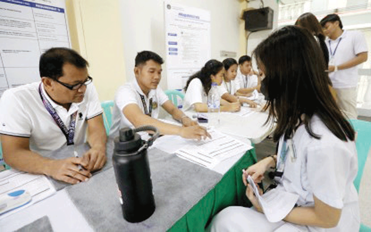 A Commission on Elections (Comelec) staff member assists students as they register as voters for the first time on March 21, 2024. The Comelec has processed over six million voter applications since the registration period started seven months ago. (PNA photo)