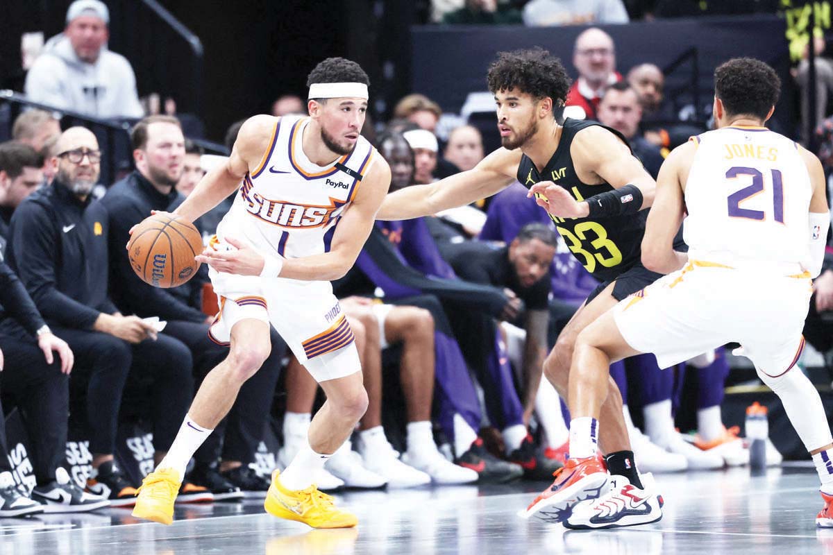 Phoenix Suns guard Devin Booker (left) uses a screen by guard Tyus Jones (right) as Utah Jazz guard Johnny Juzang defends during the third quarter of an NBA game. (Rob Gray-Imagn Images / Reuters photo)