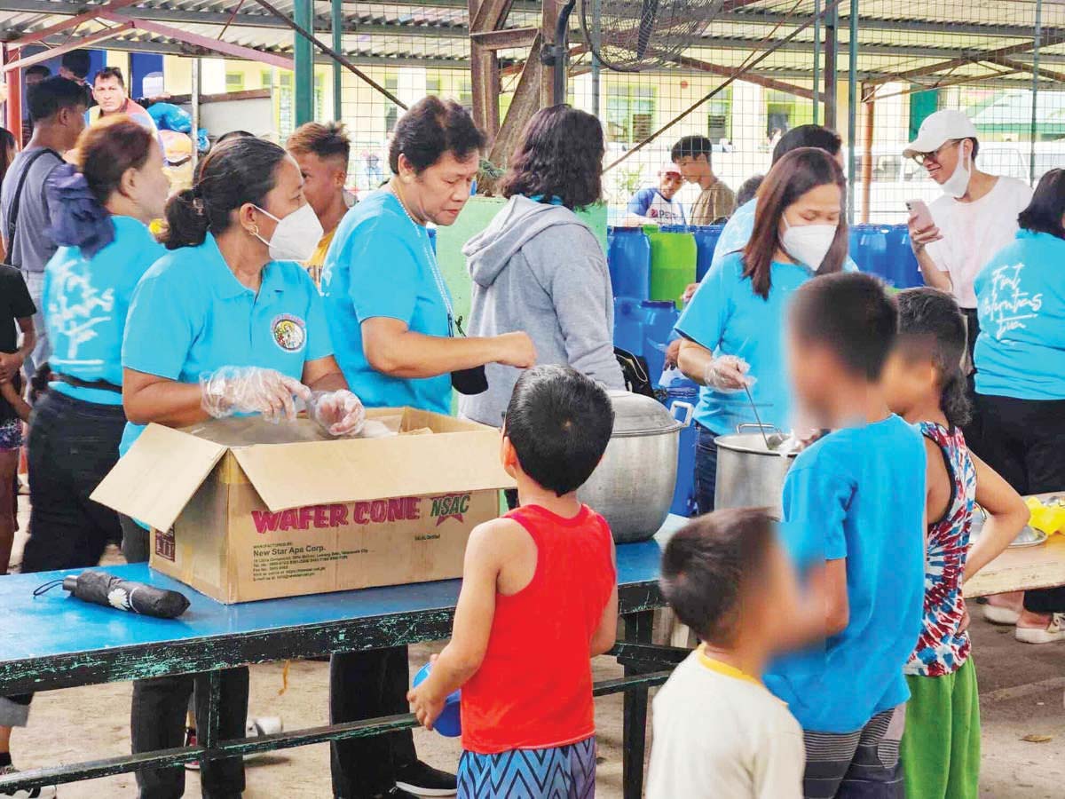 Church volunteers provide hot meals to displaced families inside an evacuation center in Negros Occidental’s La Castellana town following the explosive eruption of Kanlaon Volcano last week. Authorities ensure the timely and coordinated distribution of humanitarian assistance to affected residents while continuously monitoring other disaster relief activities. (DSWD-Western Visayas photo)