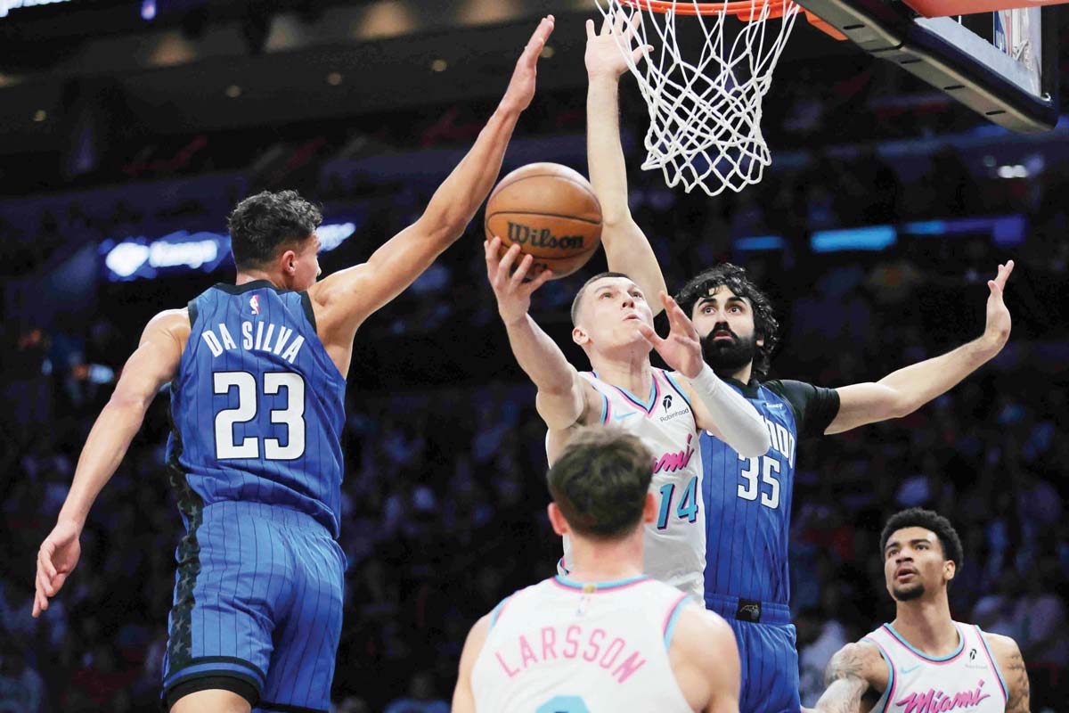 Miami Heat guard Tyler Herro (14) scores past Orlando Magic forward Tristan da Silva (23) and center Goga Bitadze (35). (Sam Navarro-Imagn Images)