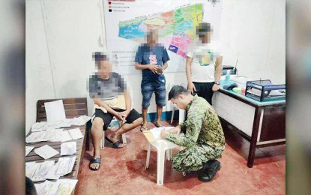 A barangay official who was arrested for "vote-buying" in Bacong, Negros Oriental answers a police investigator's questions on Saturday, May 10, 2025. The provincial prosecutor's office has dismissed the complaint for violation of Comelec Resolution No. 11104 and reverted it to the Committee on Kontra Bigay in Manila. (Police Regional Office-Negros Island Region photo)